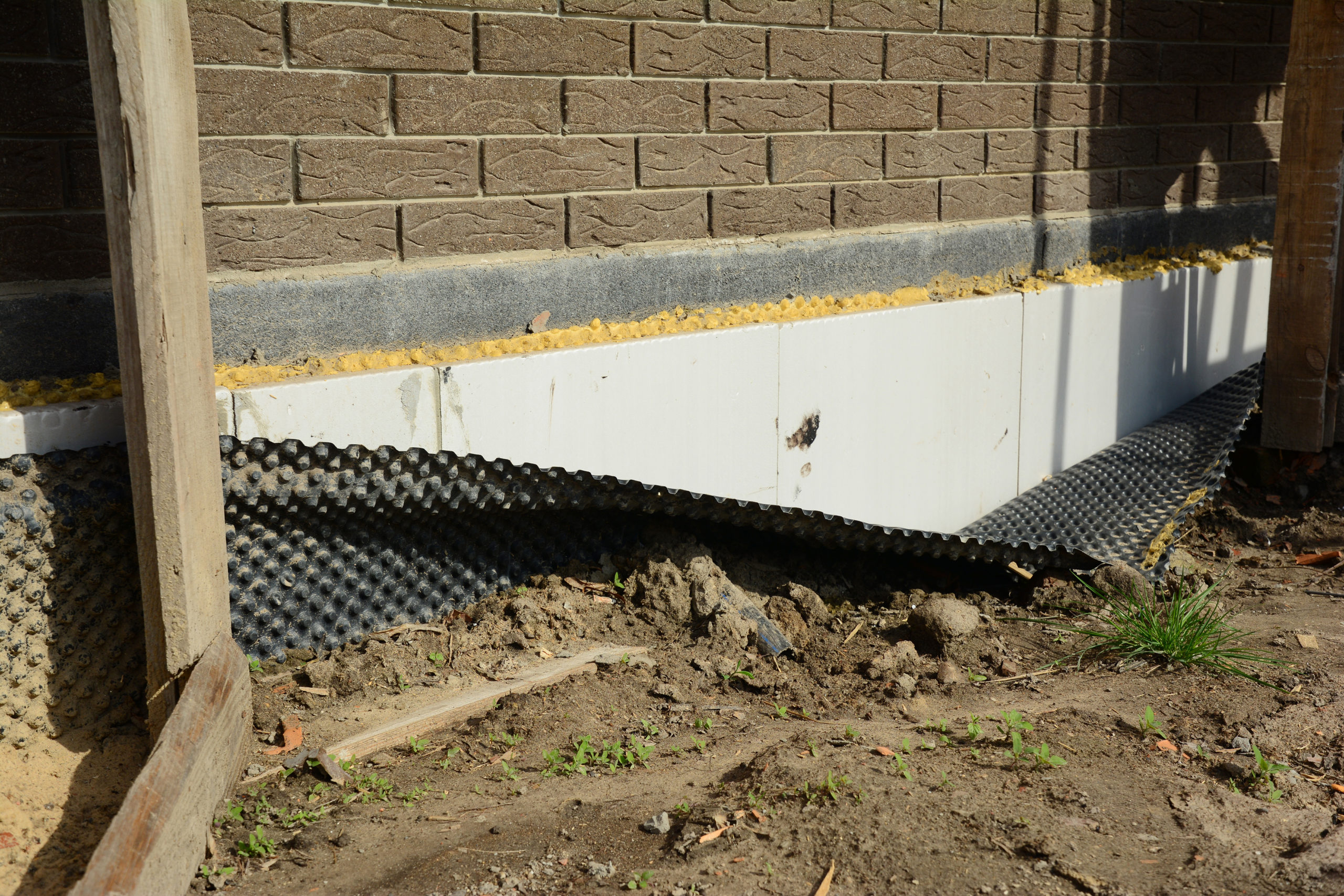 An external membrane has fallen away from the concrete foundation it was applied to.