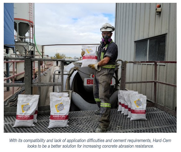 A worker is holding a bag of Hard-Cem admixture ready to put in concrete mix during batching to increase its concrete abrasion resistance.