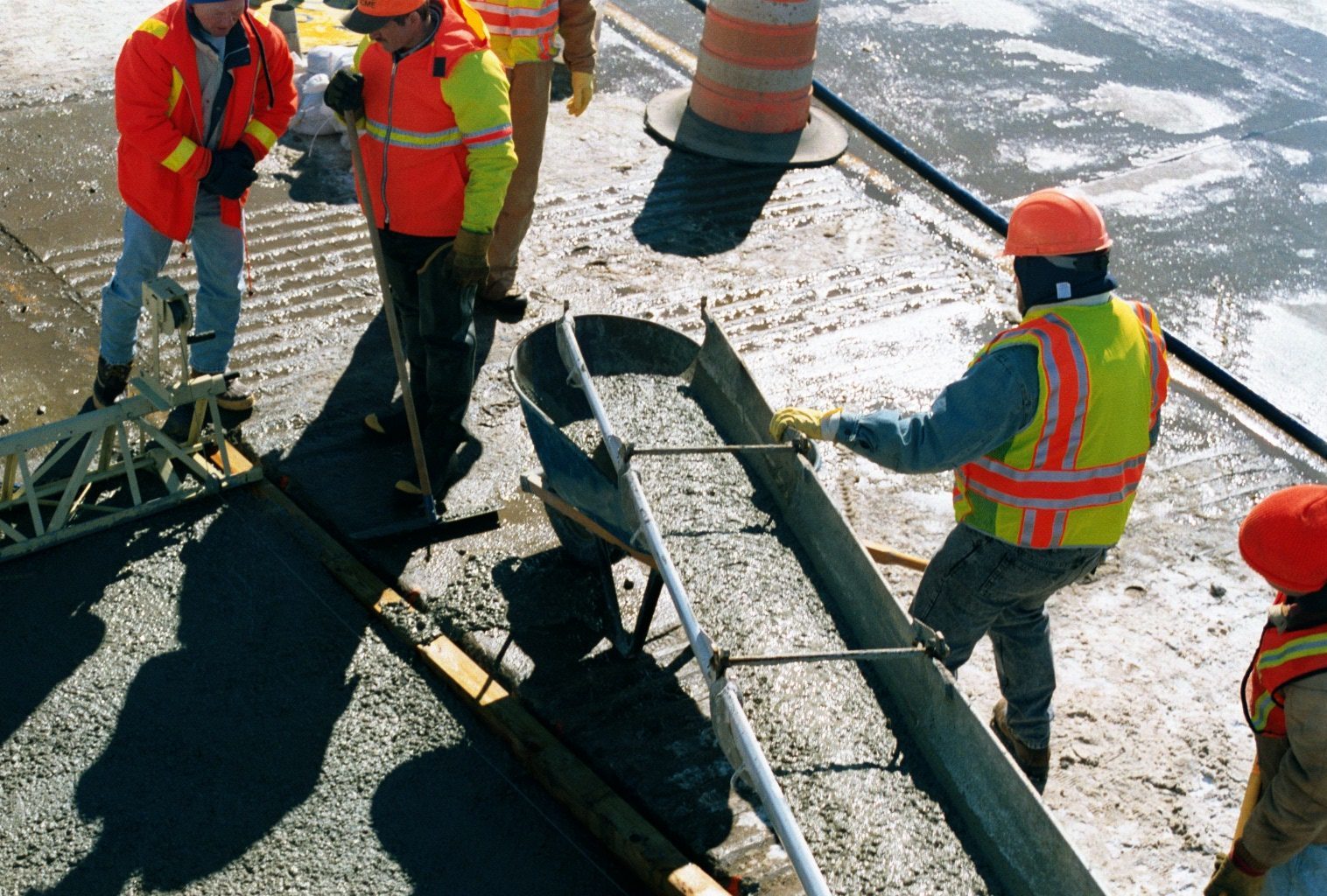 A construction worker is guiding concrete mix down into the area it needs to be poured in.